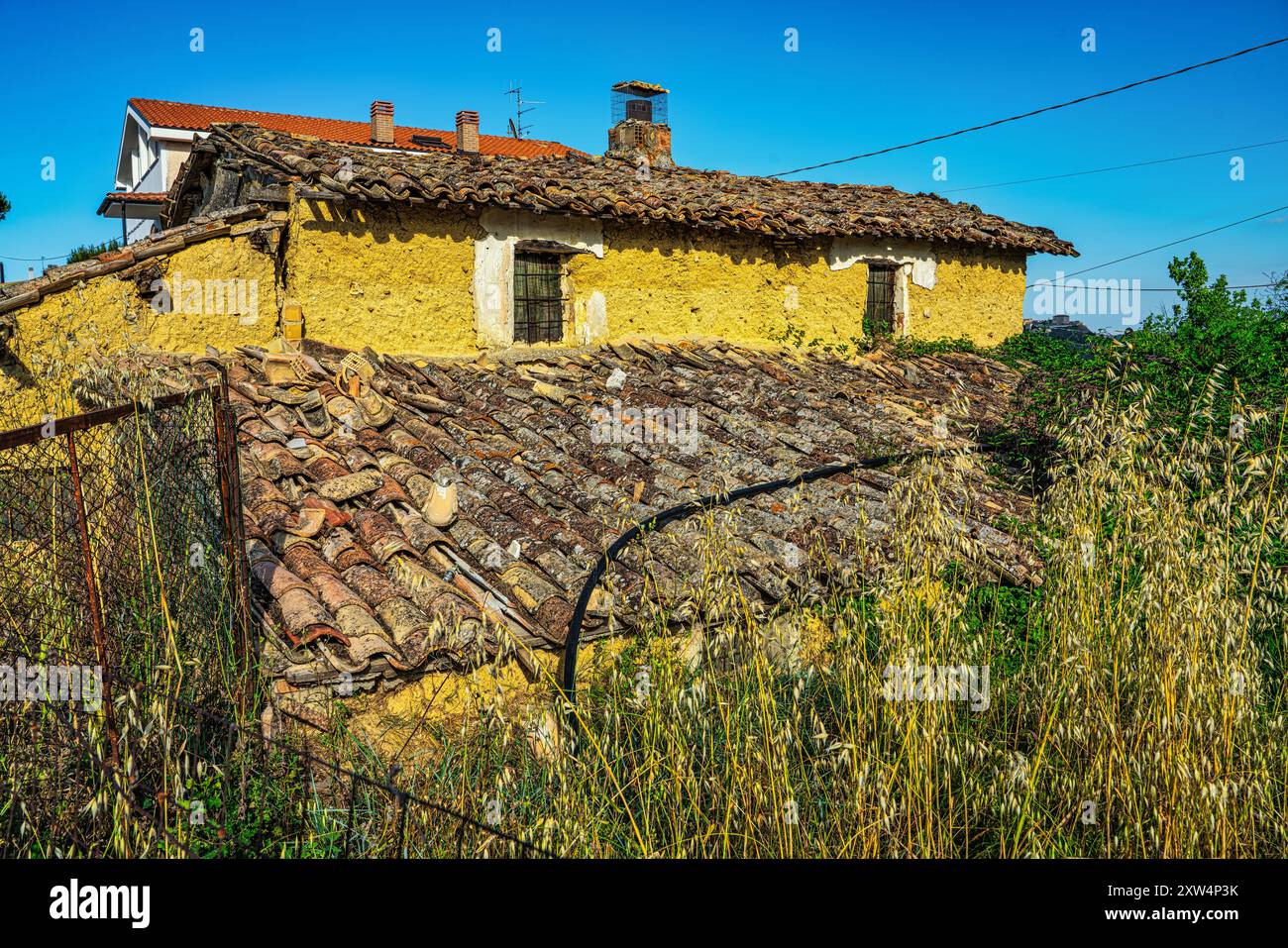 A mud house, painted yellow, now in ruins and surrounded by weeds and brambles. Colle Marcone, Province of Chieti, Abruzzo, Italy, Europe Stock Photo