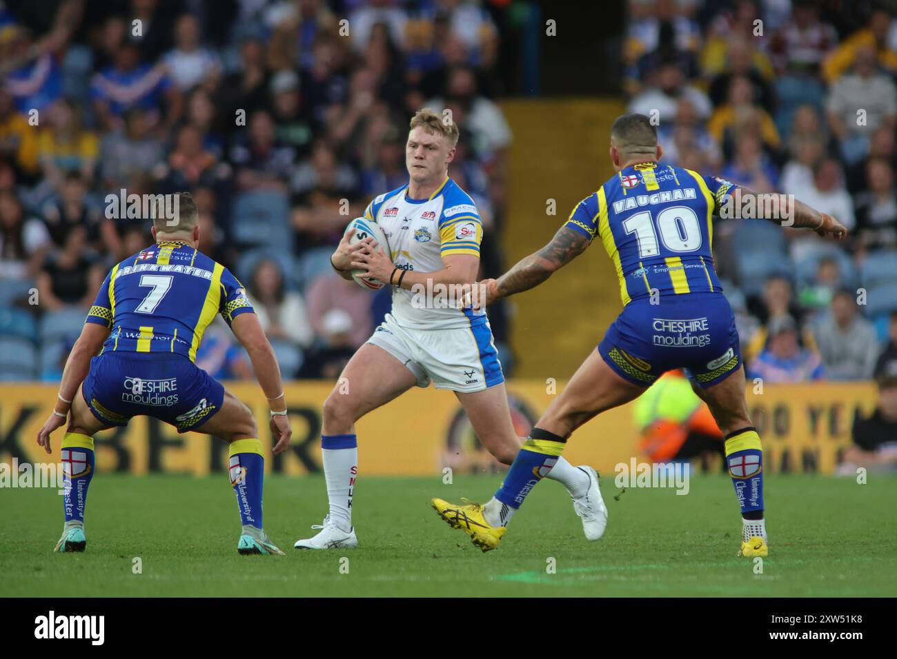 Leeds, UK. 17th Aug, 2024. Elland Road, Leeds, West Yorkshire, 17th August 2024. Betfred Super League - Magic Weekend Warrington Wolves vs Leeds Rhinos James McDonnell of Leeds Rhinos tackled by Josh Drinkwater and Paul Vaughan of Warrington Wolves Credit: Touchlinepics/Alamy Live News Stock Photo