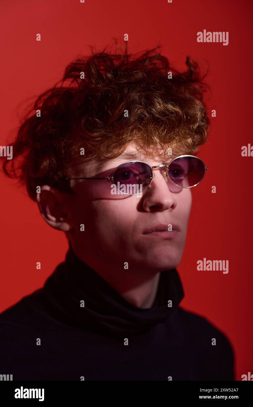 Young Man Wearing Sunglasses against Vibrant Red Background Stock Photo