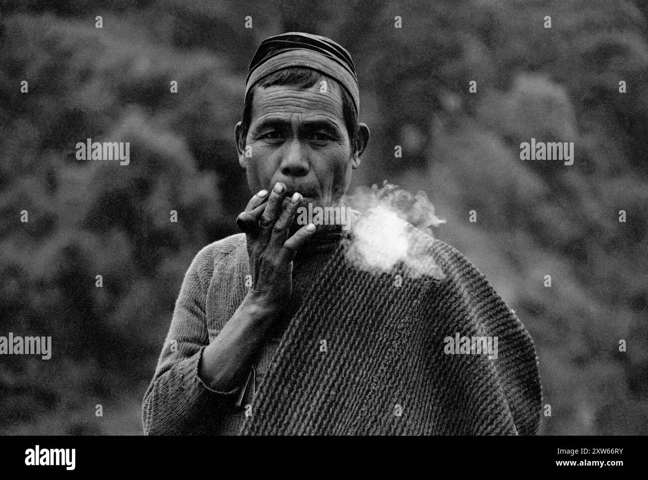 A Gurung man smokes a cheroot in the middle hills of Nepal on the Bodha Himal trek - Nepal 1990 Stock Photo