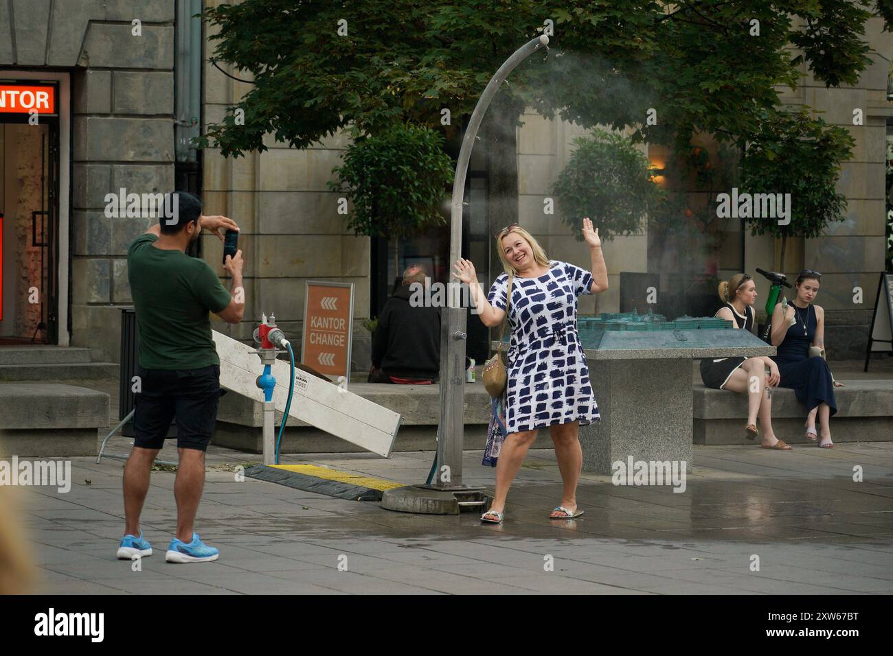 Warsaw, Poland. 17th Aug, 2024. A woman poses for a photo with a mist cooling system amid heatwave in Warsaw, Poland, on Aug. 17, 2024. Credit: Jaap Arriens/Xinhua/Alamy Live News Stock Photo