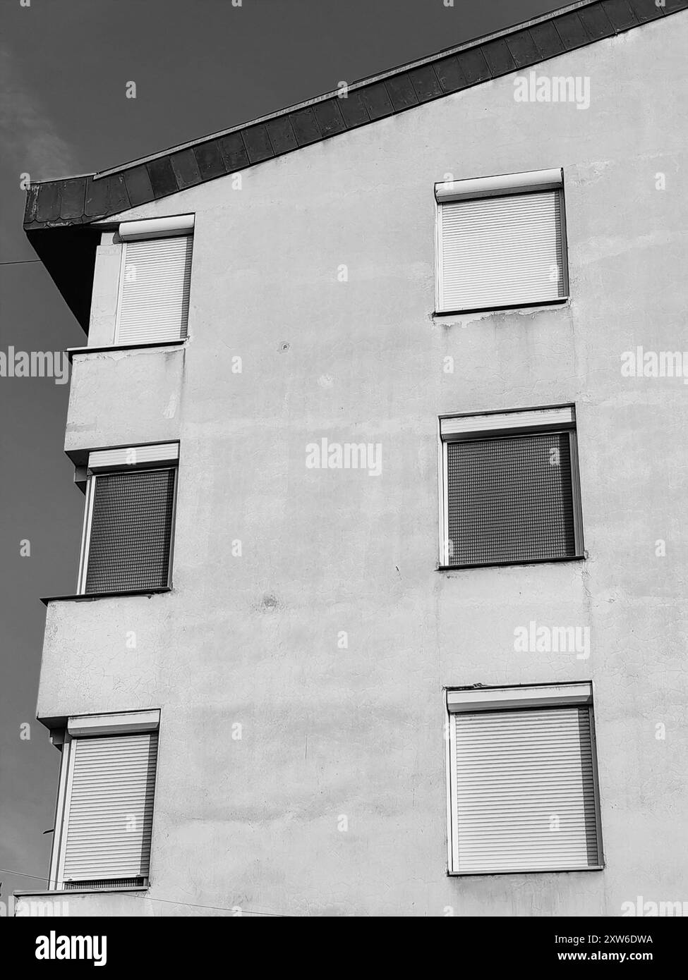 Windows with Closed Blinds: Protecting from the Sun – Sunrise and a New Dawn in the City. Symmetry of the building. Black and white. Stock Photo