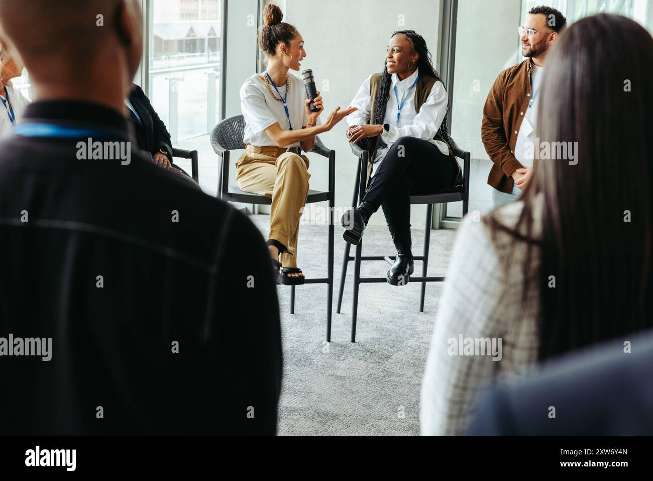 Group of professionals engaging in a business panel discussion and debate, sharing insights and ideas in a modern conference setting. Stock Photo