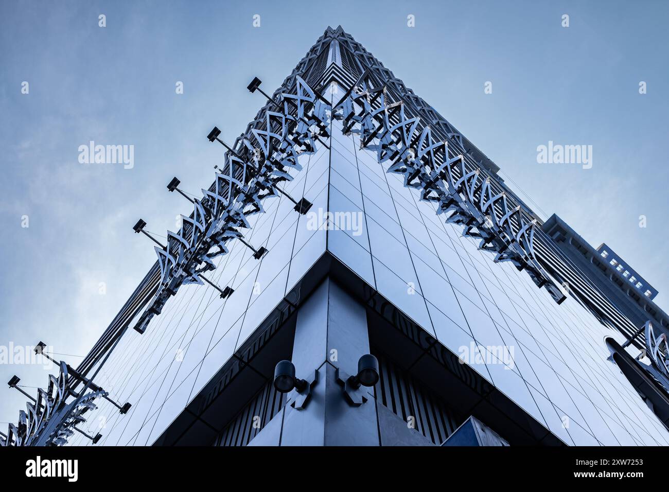 Angled view of a large, window covered building corner against a blue sky. Modern business center. Fragment of an office building made of glass, futur Stock Photo
