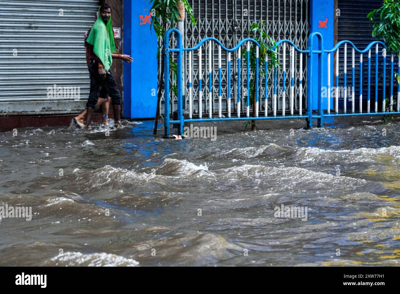 Commuters wade through a flooded street during monsoon rains in Kolkata ...