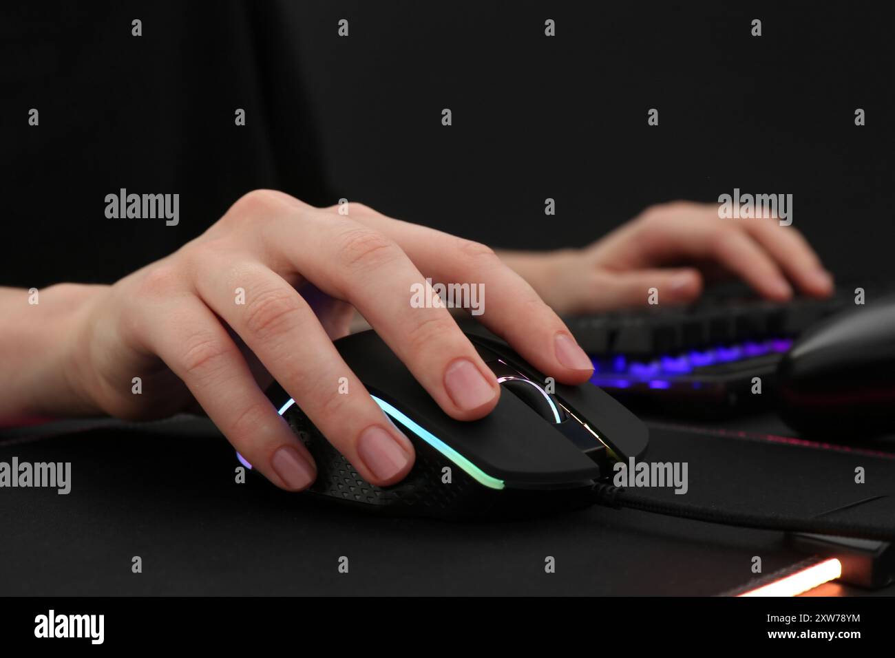 Gamer using modern wired computer mouse at dark table, closeup Stock Photo