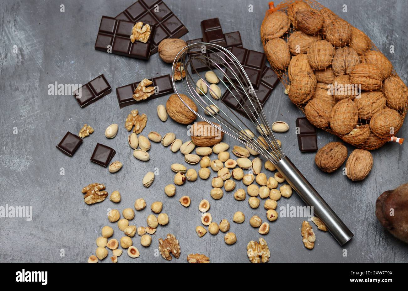 Chocolate bars, walnuts and hazelnuts on a gray background. Stock Photo