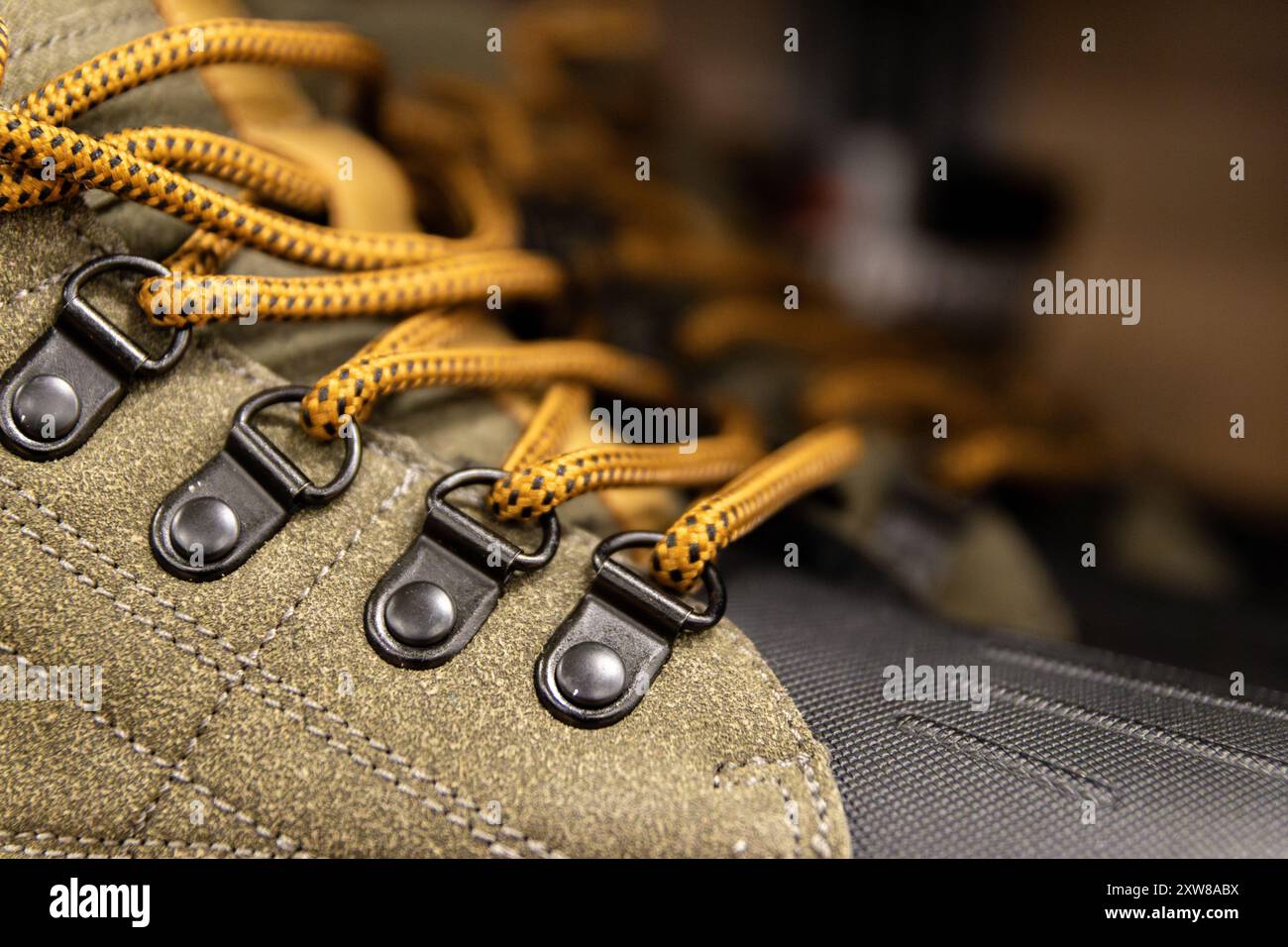 Close-up of olive green hiking boot with detailed focus on metal eyelets and bright yellow laces. Taken in Toronto, Canada. - Stock Image