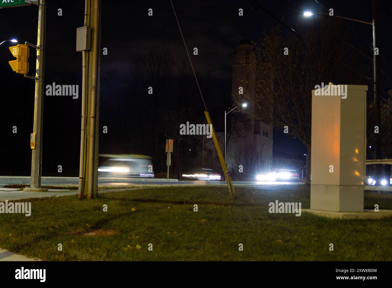 Nighttime urban scene captures motion blur of a speeding car with streetlights casting a soft glow on the pavement. Taken in Toronto, Canada. - Stock Image