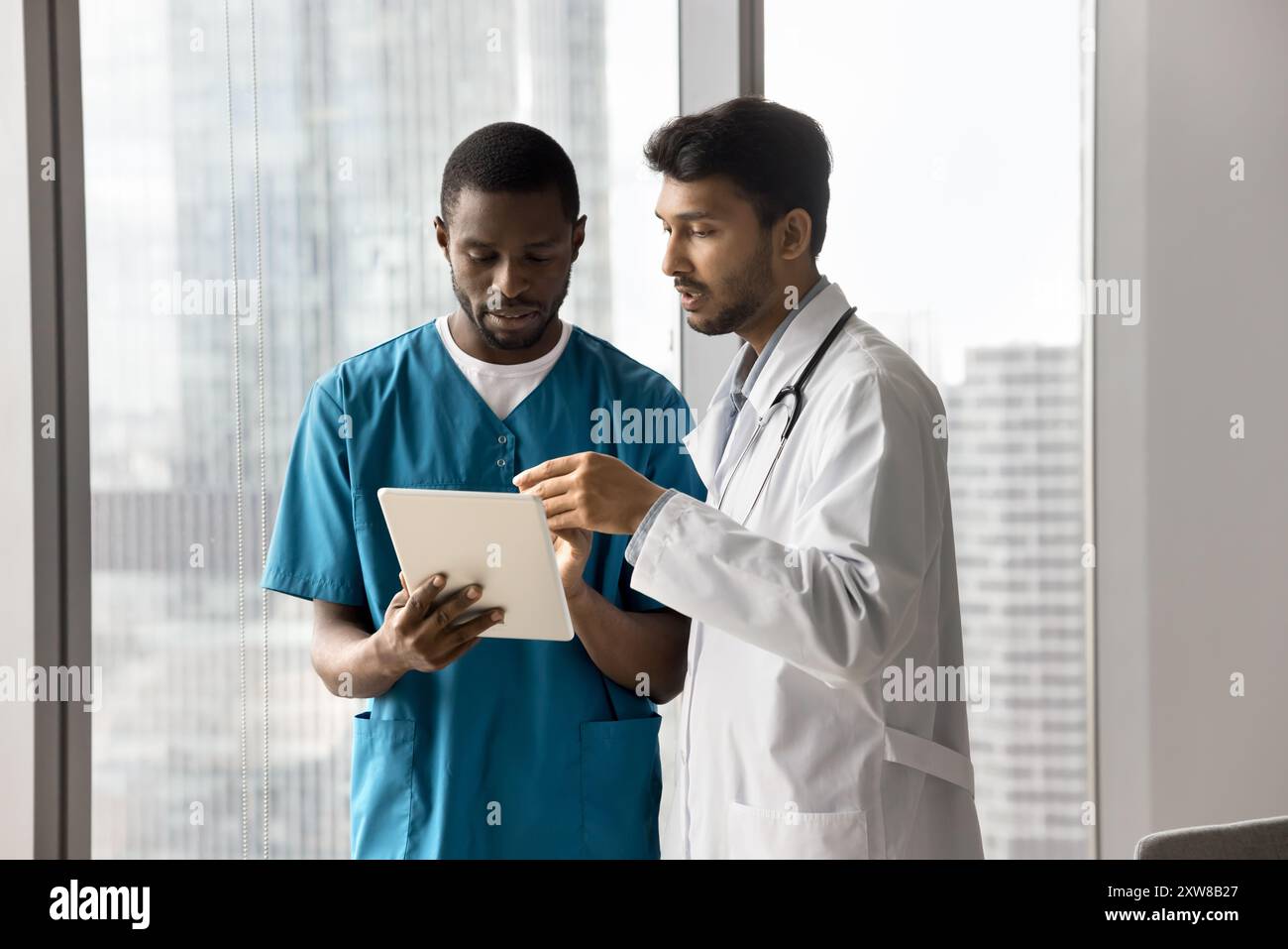 Two medical professionals collaborating, examining information on tablet Stock Photo