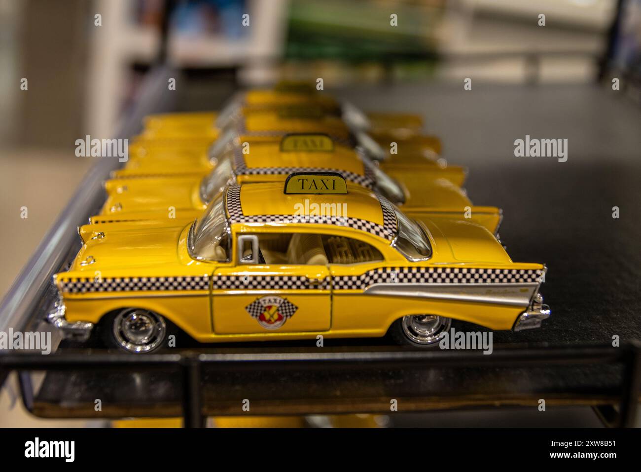 Row of miniature yellow taxi cabs lined up on a shelf - classic New York City Checker Taxi design. Taken in Toronto, Canada. - Stock Image