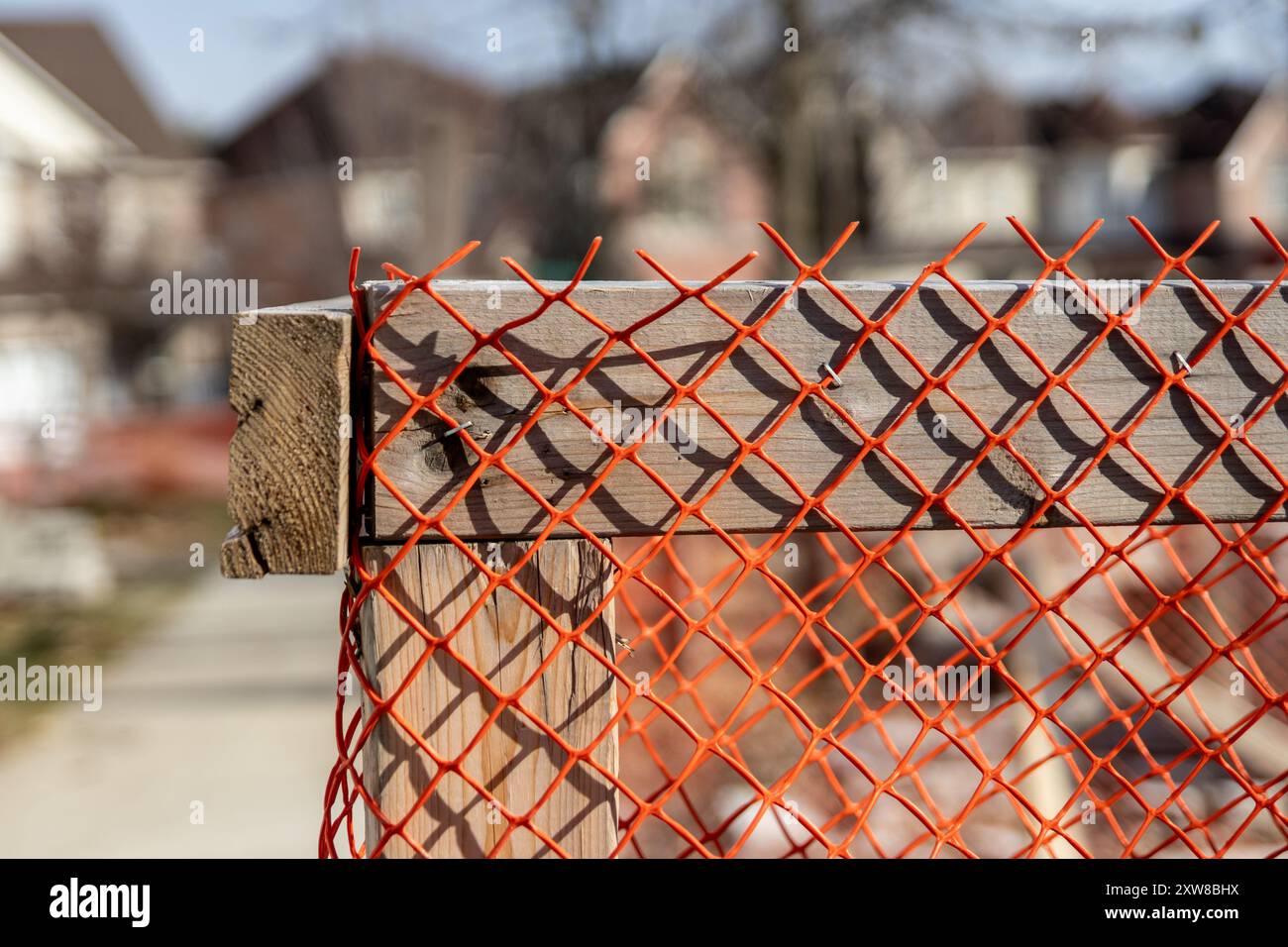 Vibrant orange safety netting attached to a weathered wooden post. Taken in Toronto, Canada. - Stock Image