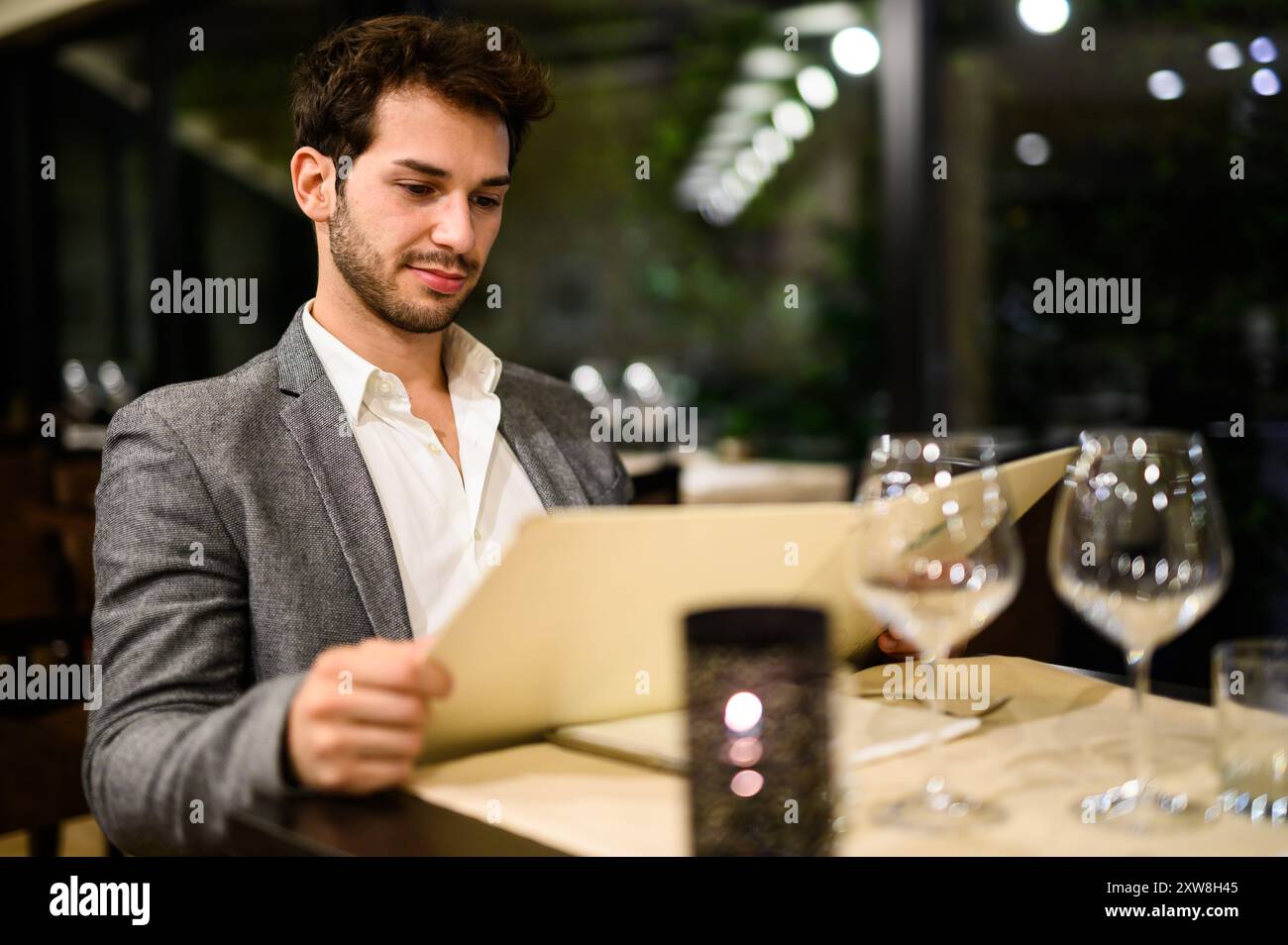 Sophisticated young man selecting a dish from a menu in a posh dining setting Stock Photo