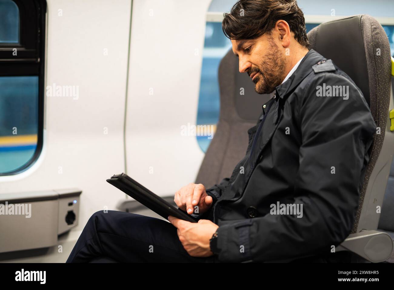 Professional man engages with a digital tablet while commuting on a train Stock Photo