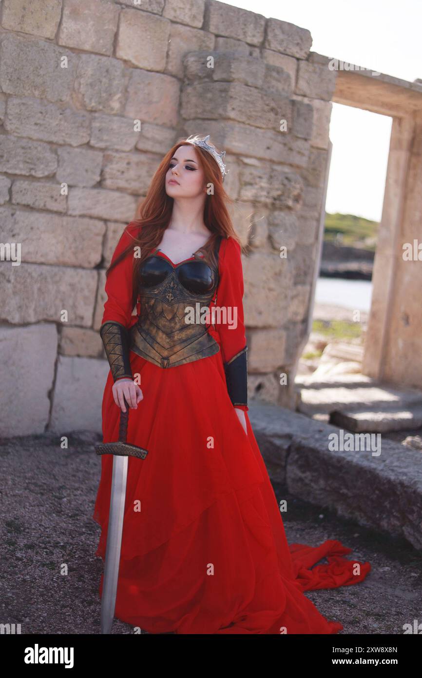 Medieval woman with red hair as a warrior with war paint with sword in  summer in front of an old castle ruin, with leather corset and cloak Stock  Photo - Alamy
