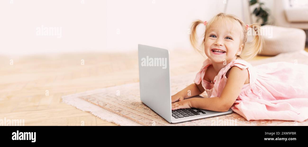 Adorable little girl using laptop lying on floor Stock Photo - Alamy