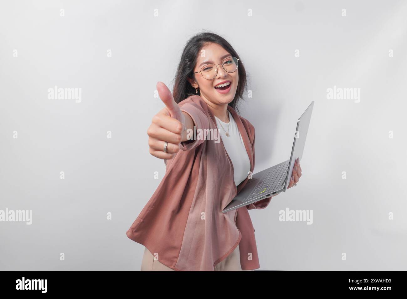 Cheerful young Asian business woman showing thumbs up and holding ...