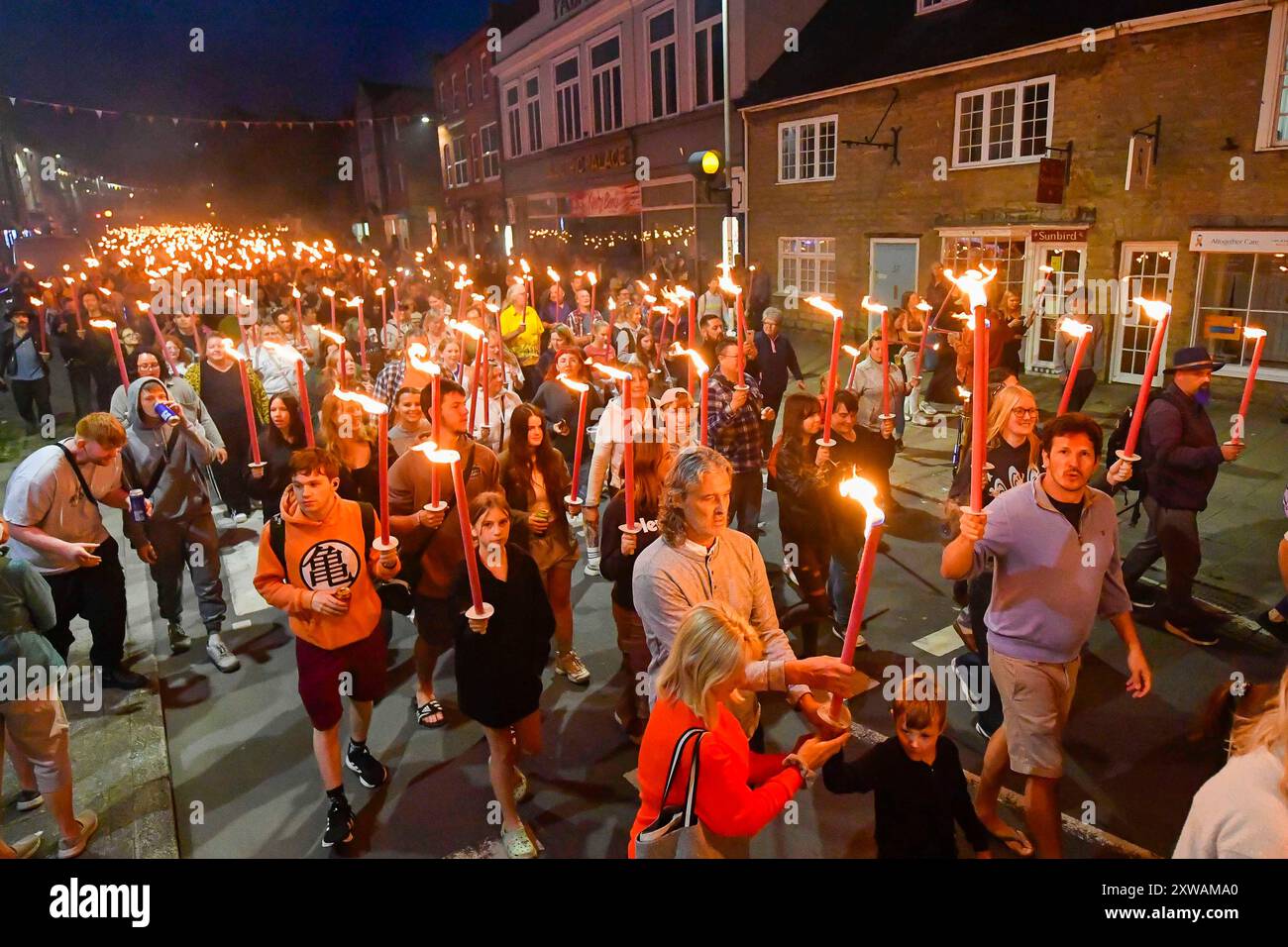 Bridport, Dorset, UK. 18th August 2024.  Hundreds of people carrying flaming torches take part in the annual Bridport Carnival Torchlight Procession.  The two mile procession started at Bridport Town Hall and finished at East Beach at West Bay in Dorset.   Picture Credit: Graham Hunt/Alamy Live News Stock Photo