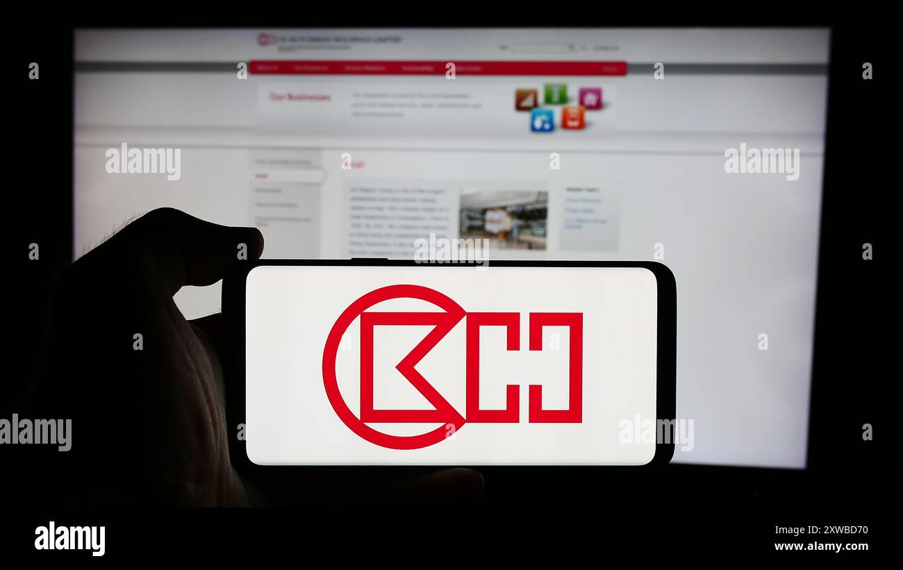 Person holding cellphone with logo of Hong Kong company CK Hutchison Holdings Limited in front of business webpage. Focus on phone display. Stock Photo