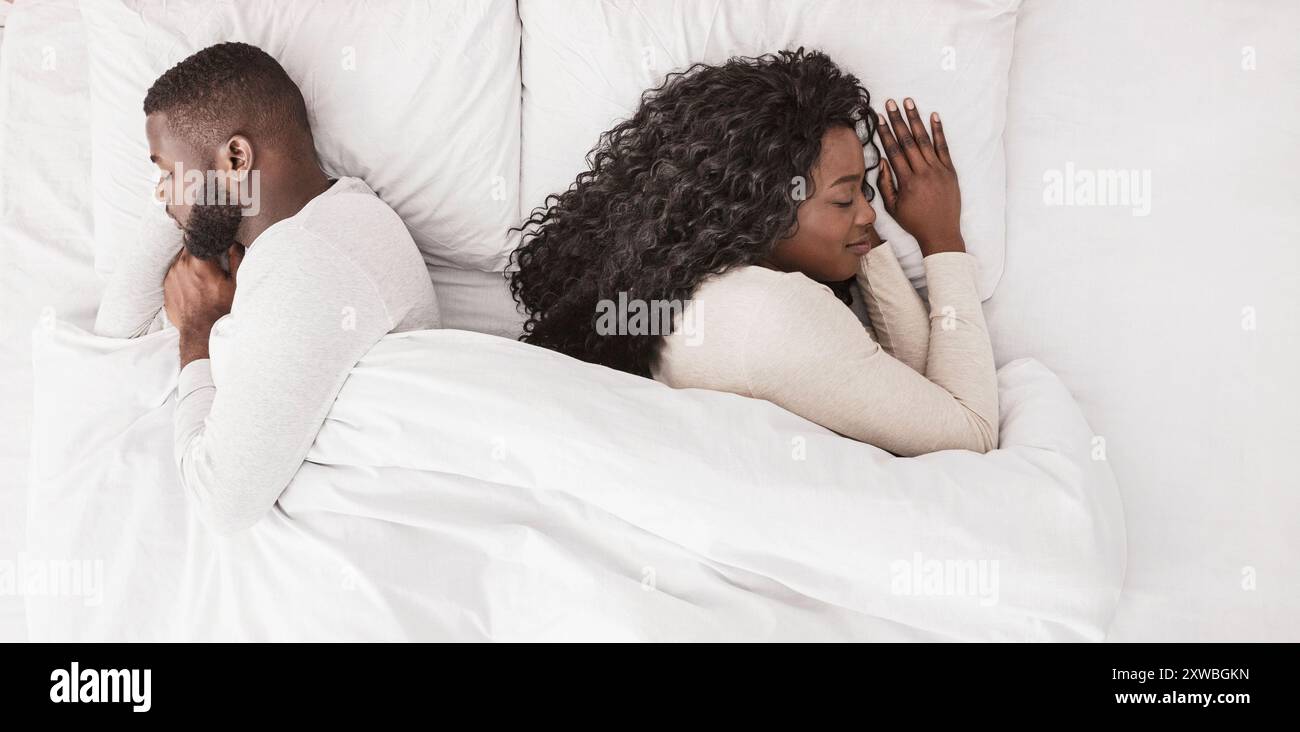 Young afro couple napping back to back in confortable bed Stock Photo
