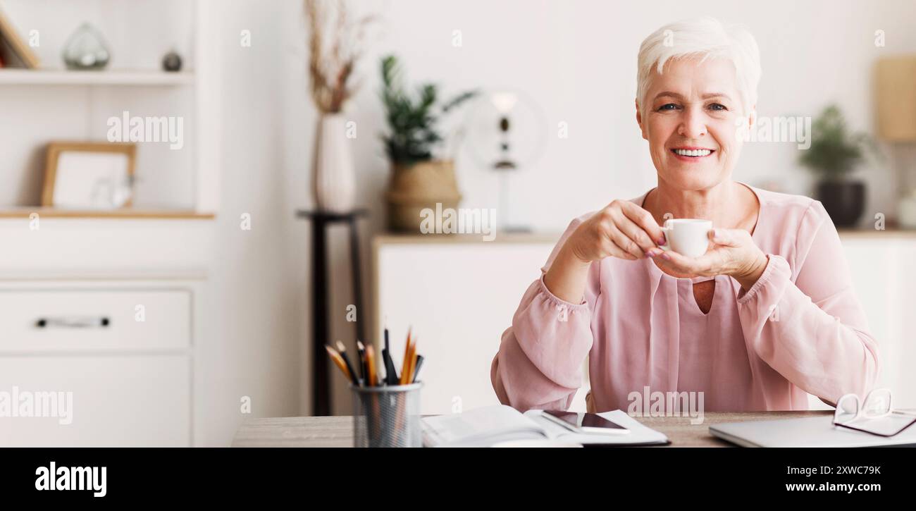 Peaceful aged lady having coffee break while working Stock Photo