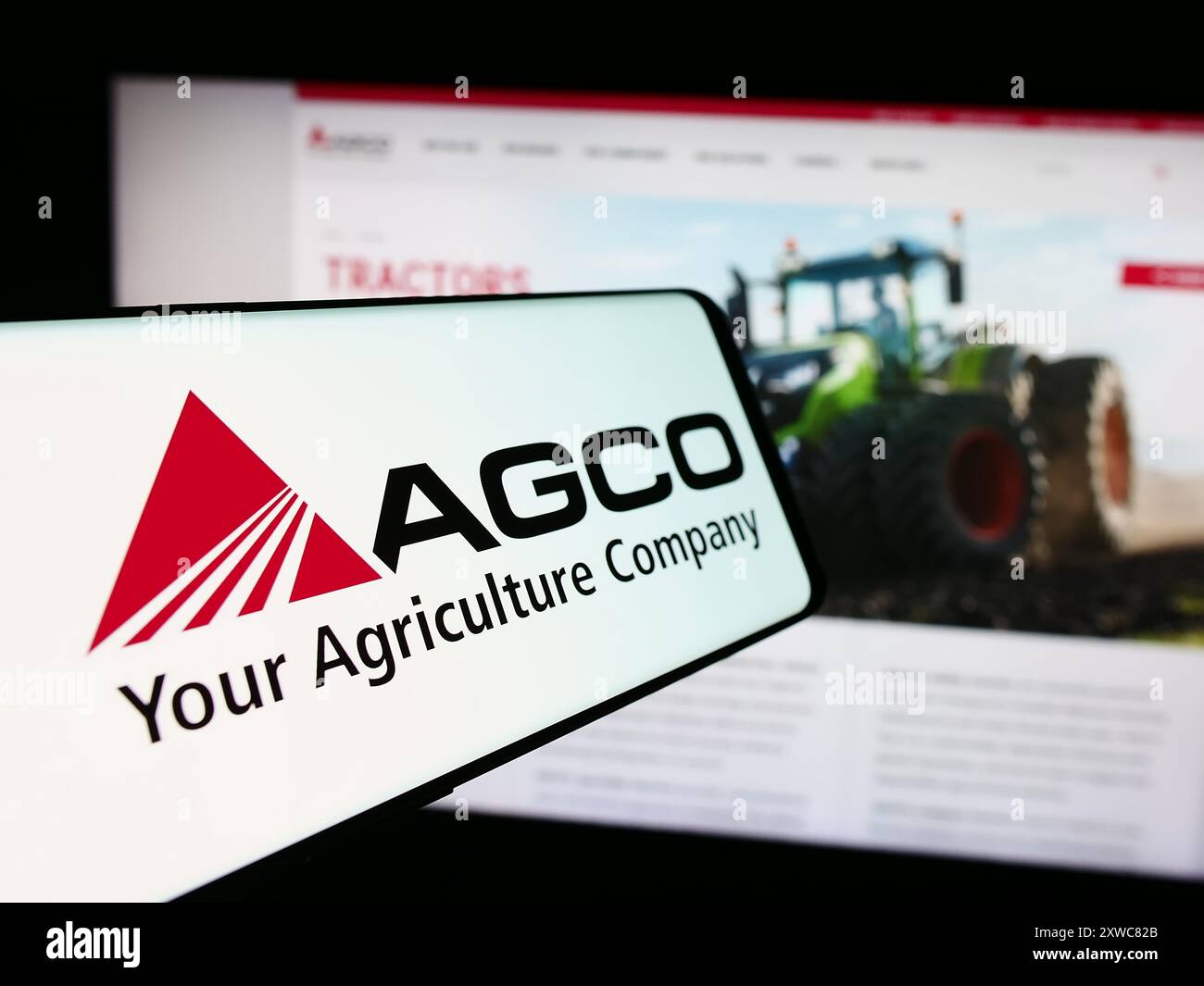 Mobile phone with logo of American agricultural machinery company AGCO Corporation in front of website. Focus on center-left of phone display. Stock Photo