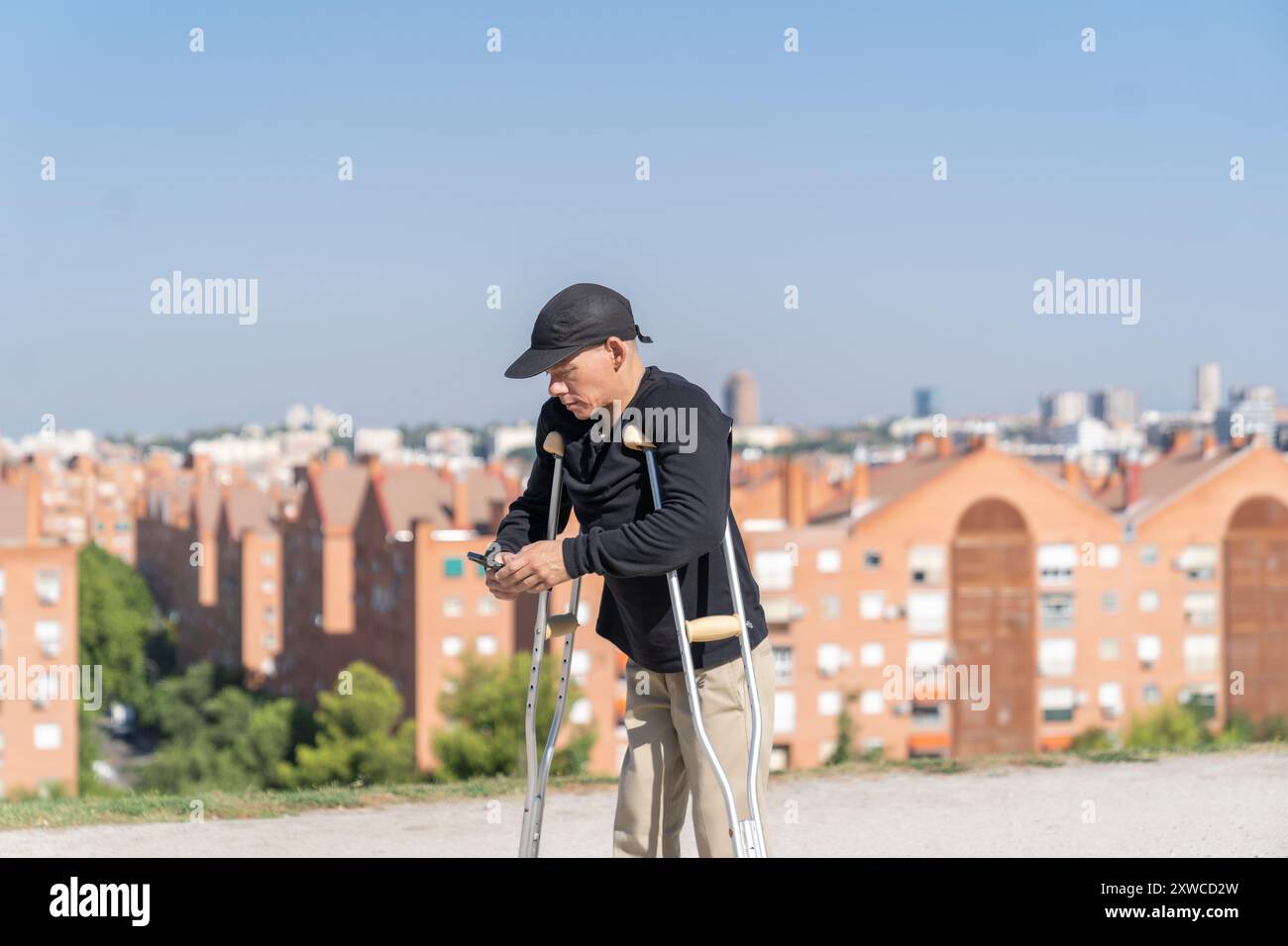 disabled man using his smartphone while walking with his crutches Stock Photo