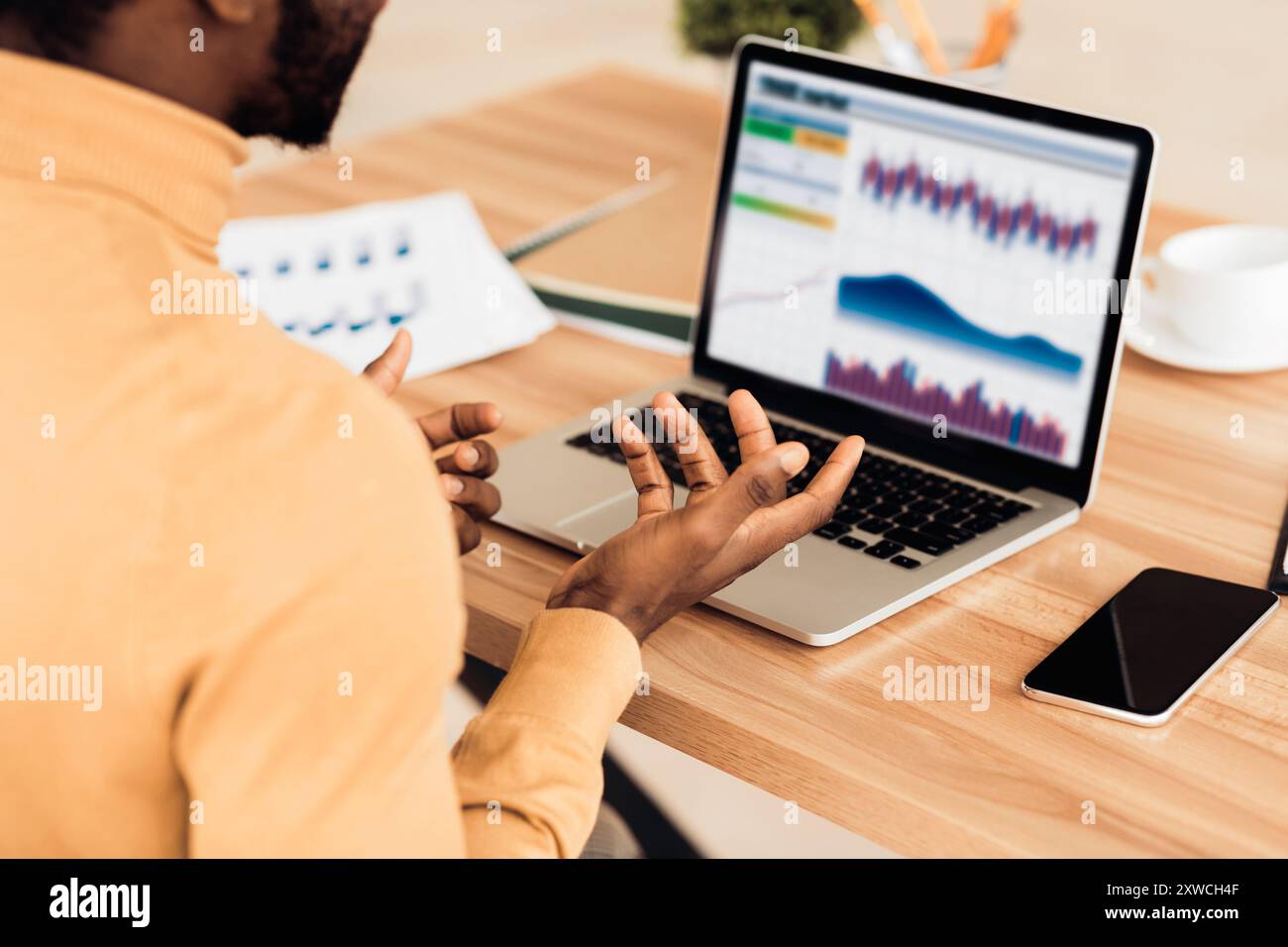 Stressed afro businessman looking at graphs on screen Stock Photo