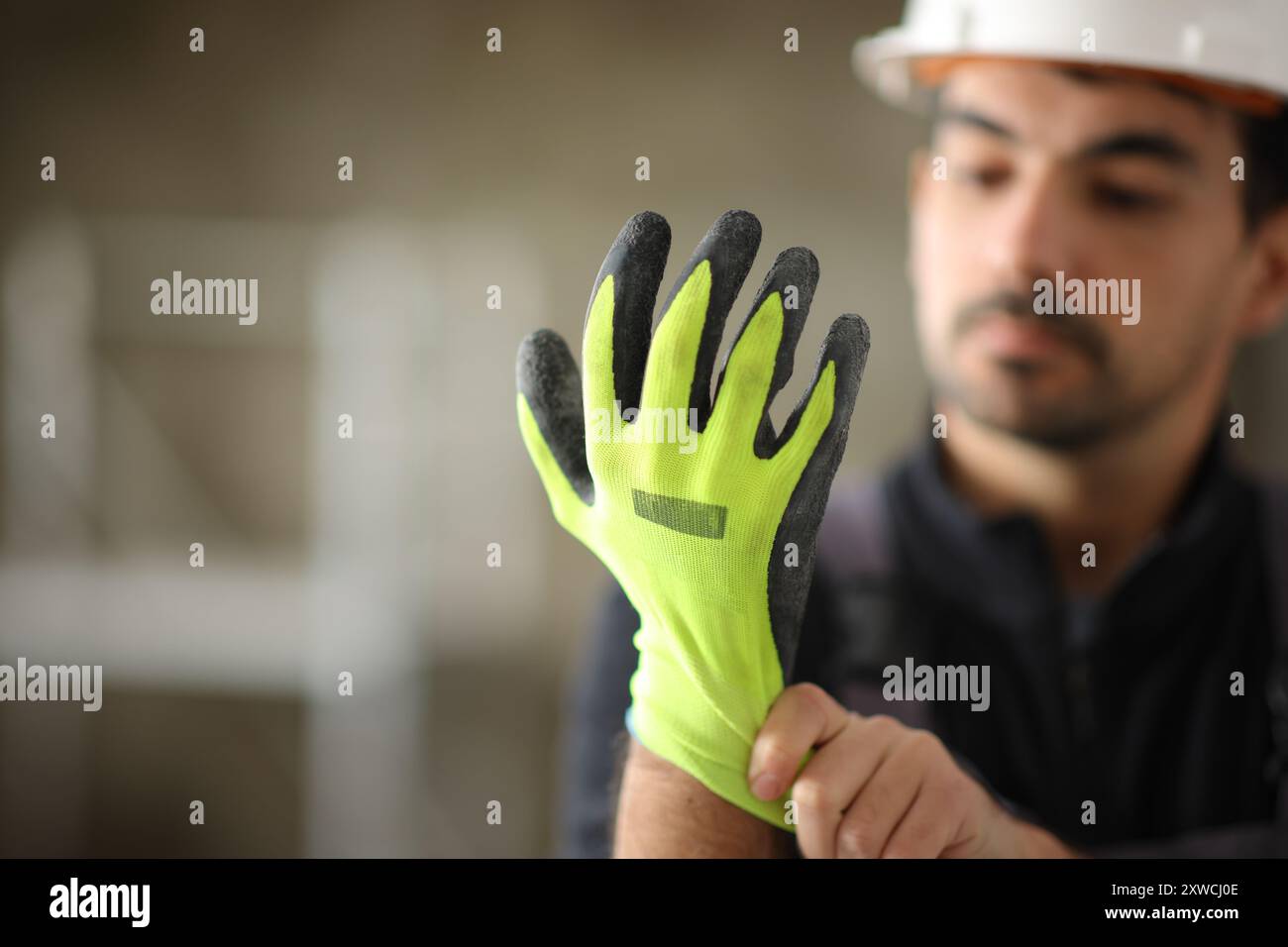 Construction worker putting protective glove before work in a house under reform Stock Photo