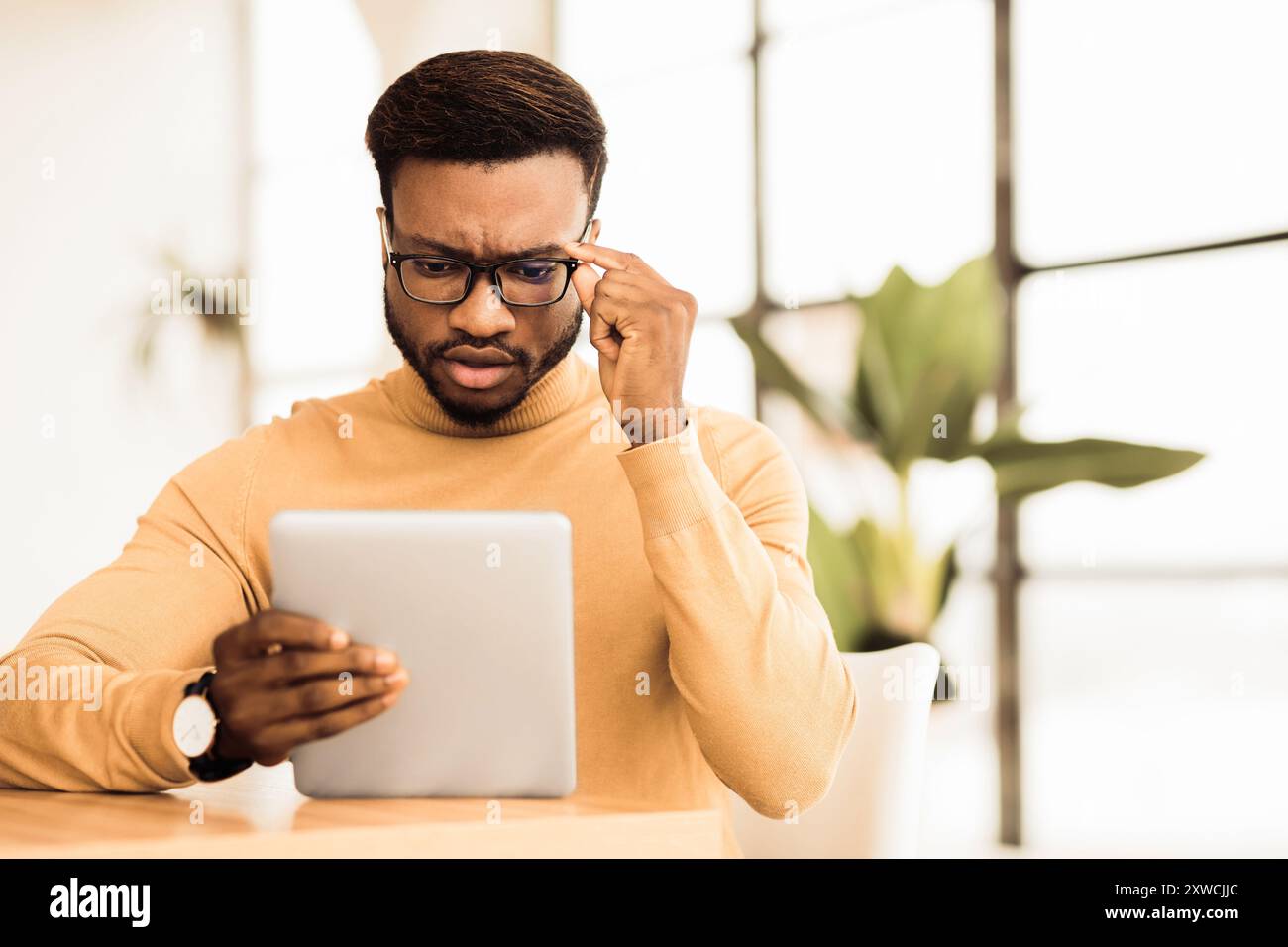 Surprised young afro manager looking at his tablet Stock Photo