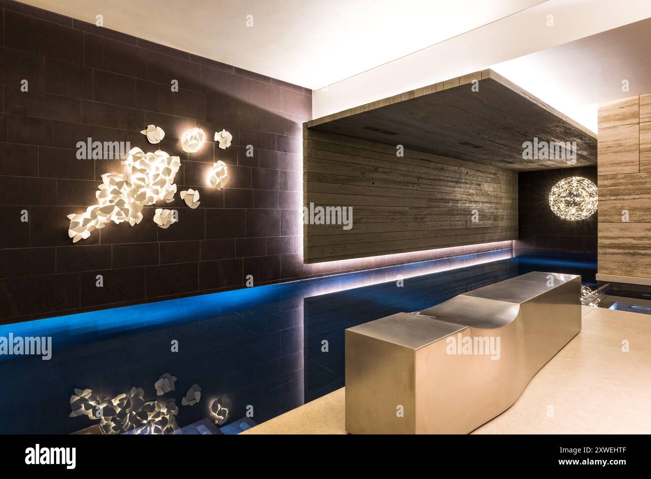 Swimming pool with abstract light installation and poolside seating in luxury modern British home. London, UK Stock Photo