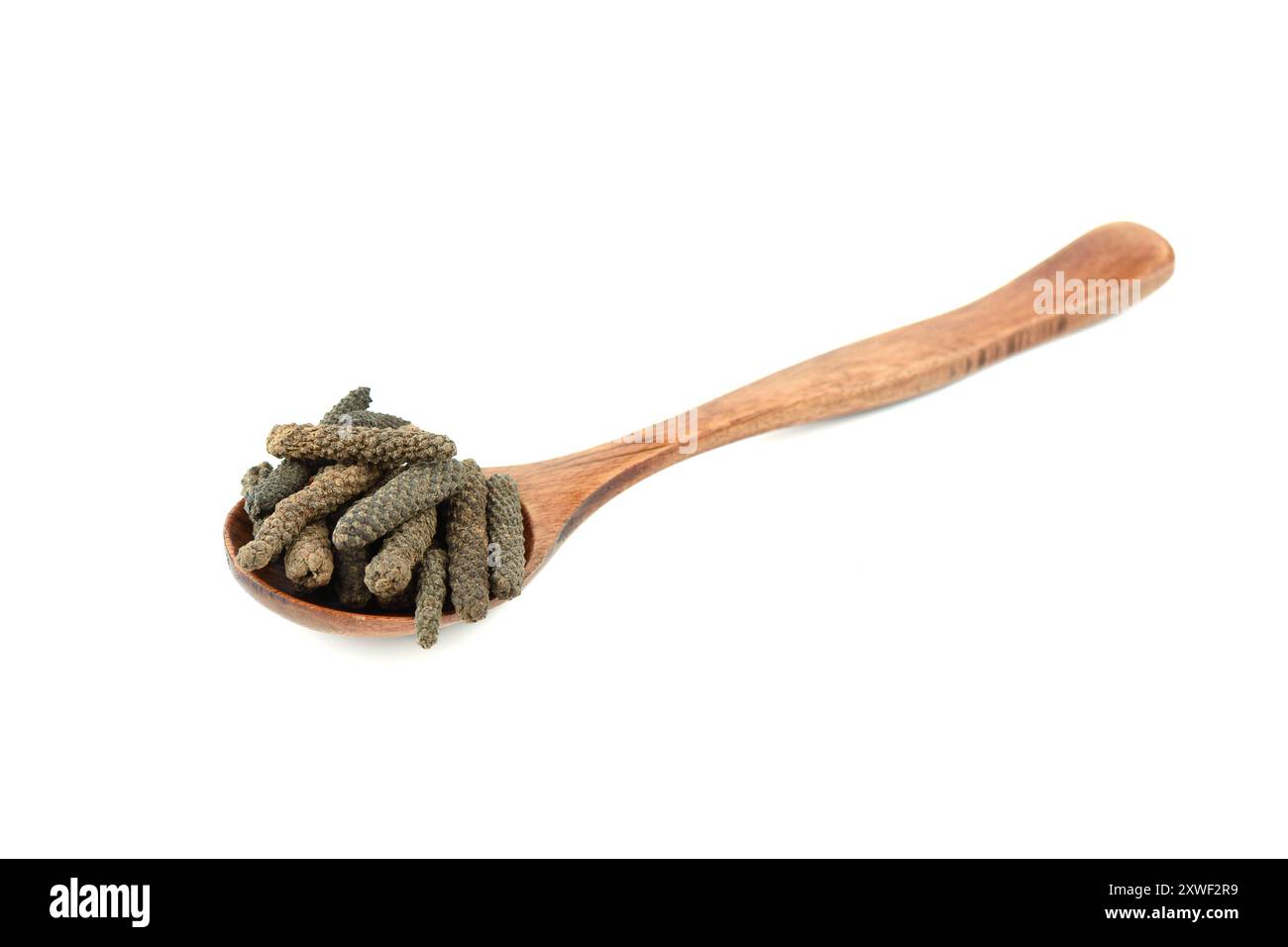 Wooden spoon full Long pepper or Pippali pepper on a white background. Long pepper, lat. Piper longum, is the fruit of an evergreen shrub of the peppe Stock Photo