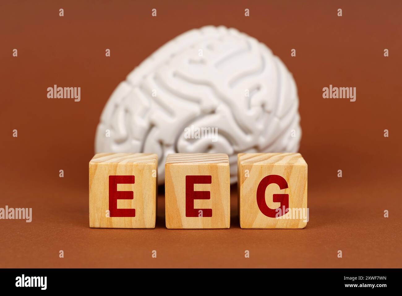 A stylized representation of brain activity, featuring wooden blocks spelling EEG in front of a sculpted brain, capturing the essence of neuroscience. Stock Photo