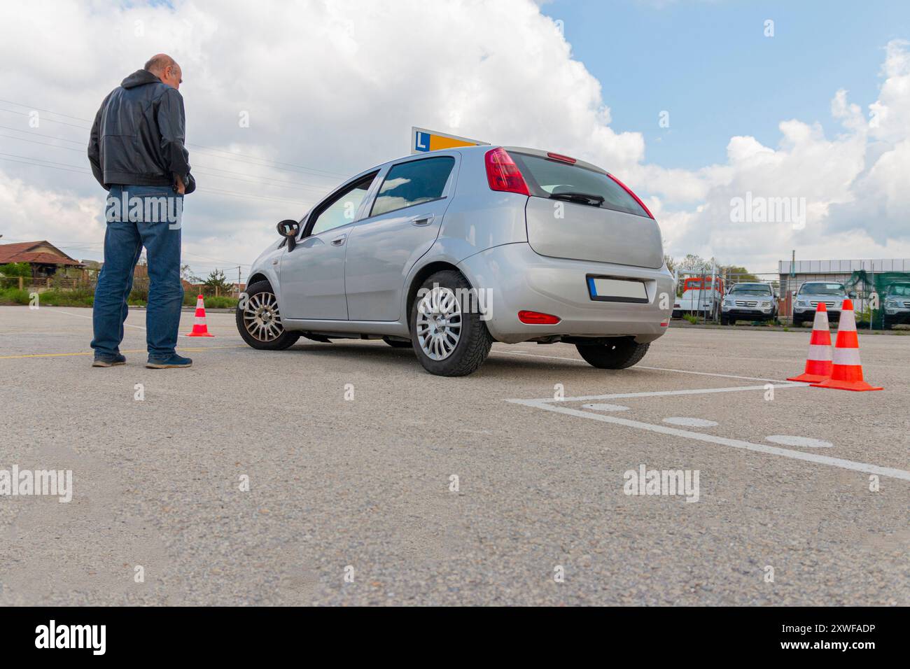 Instructor watching candidate during her practise for a driving testat day on the polygon. Stock Photo