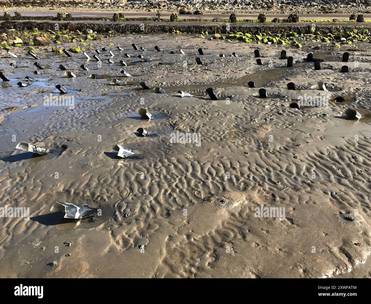 Off cuts of guttering on a sandy beach. Used as crab traps crab shelters by fishermen anglers. Concept: hazards, plastic pollution,  ghost fishing. Stock Photo