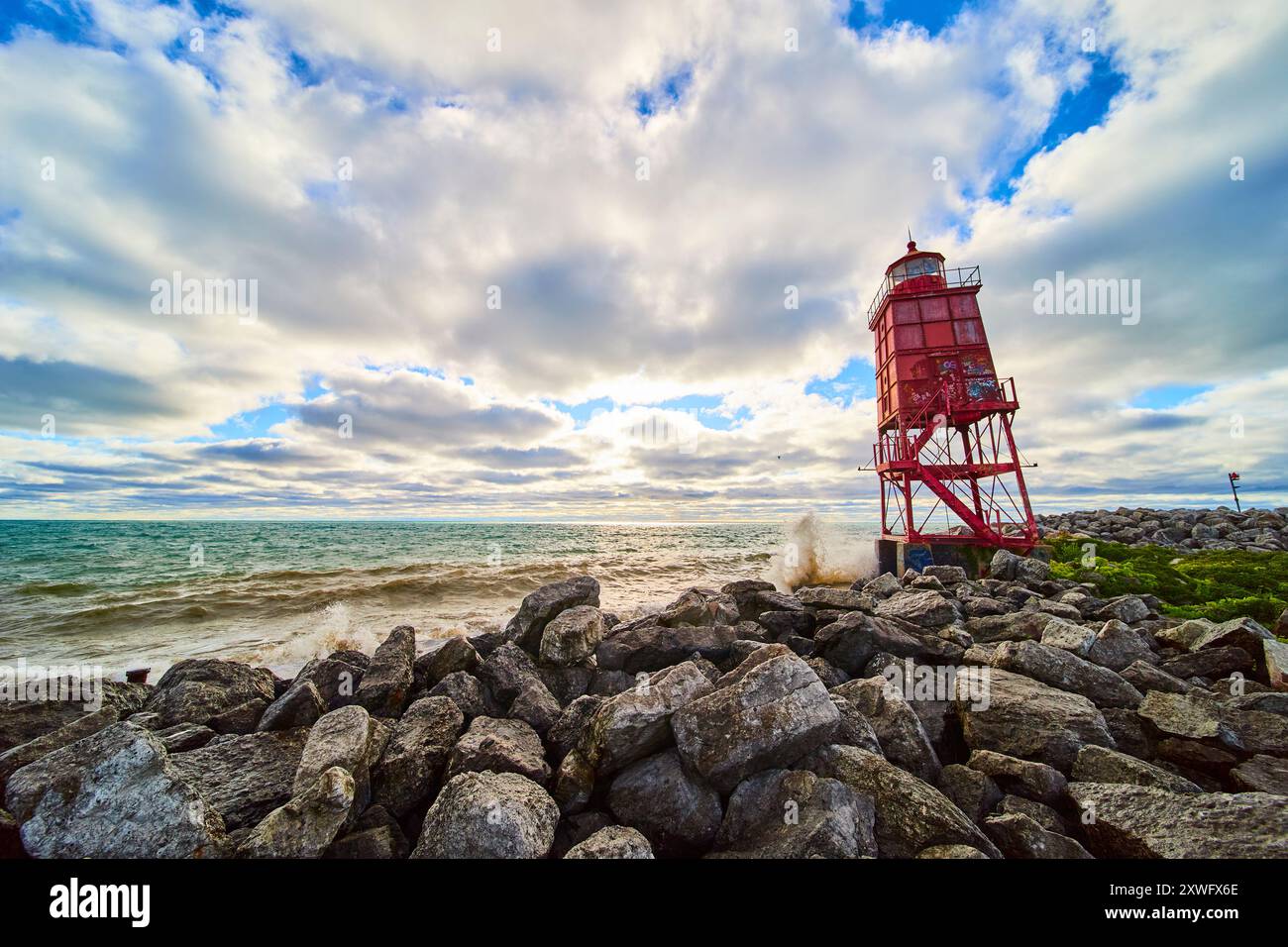 Red Lighthouse on Rocky Shoreline with Crashing Waves at Sunrise Stock Photo