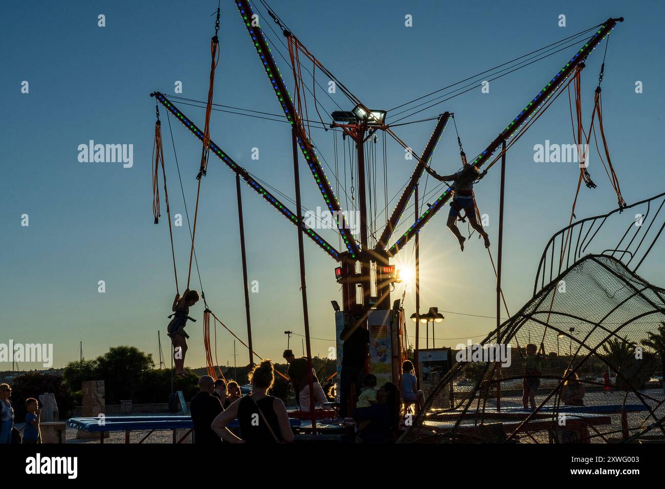 Silhouettes of kids bungee jumping at amusement park in the town of Alvor, Algarve, Portugal, Europe. Stock Photo