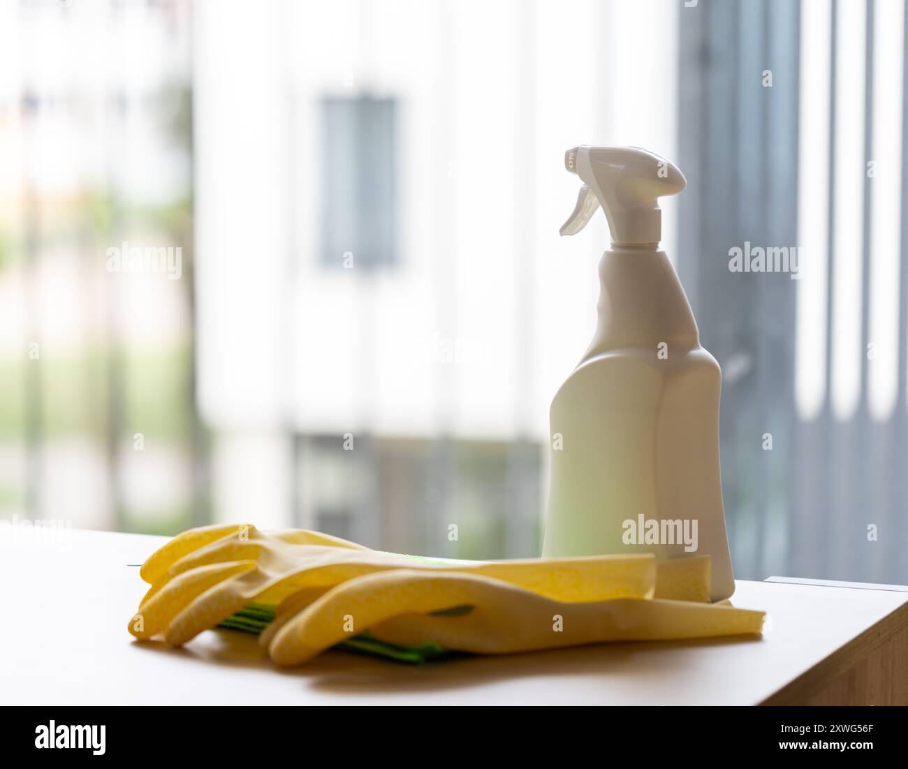 cleaning agent in white spray bottle on table, house cleaning concept against clean window Stock Photo