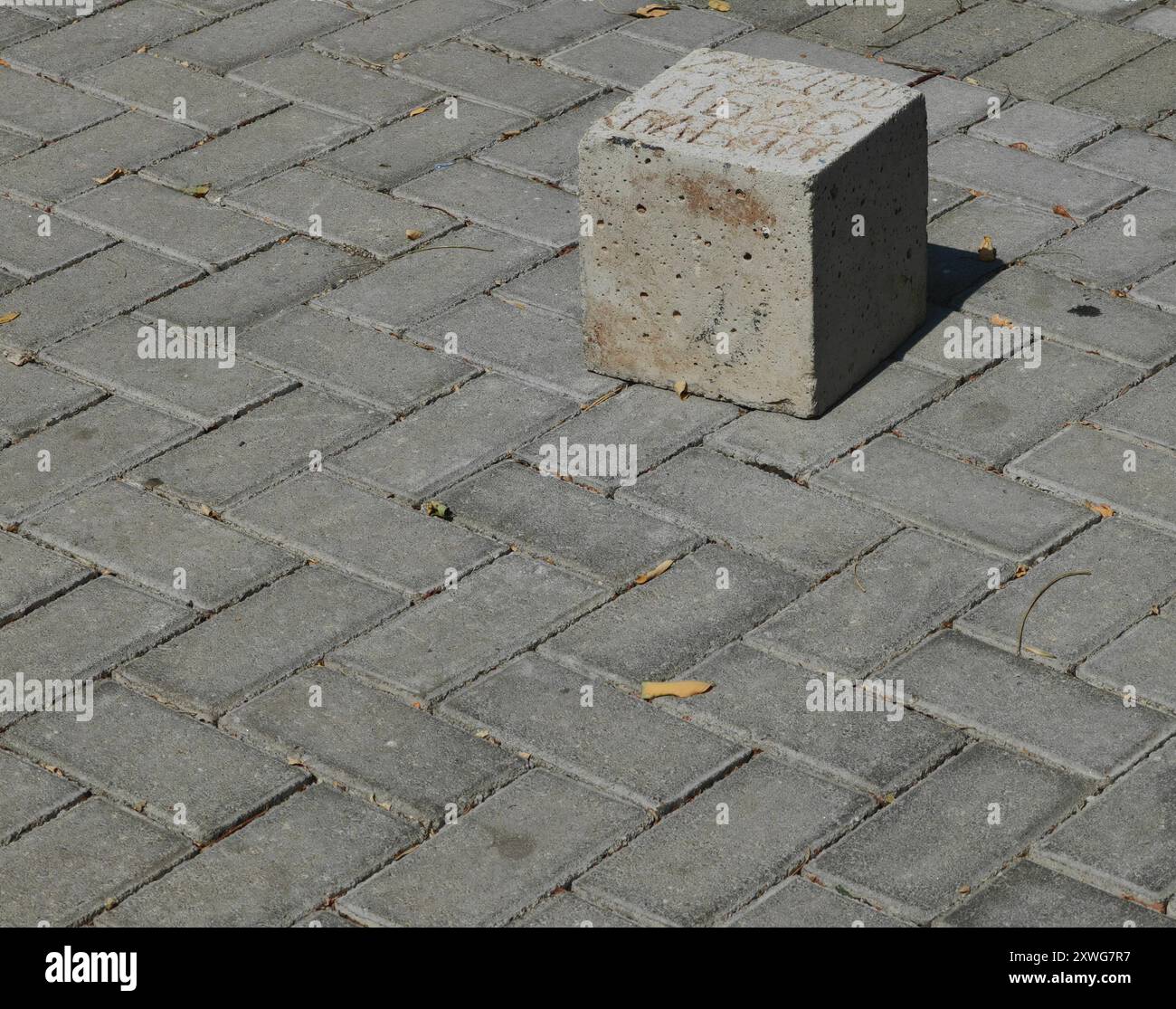 Square Stone on the Pavement: Pattern, Texture, and the Play of Light and Shadow – Burdens Concept. Stock Photo