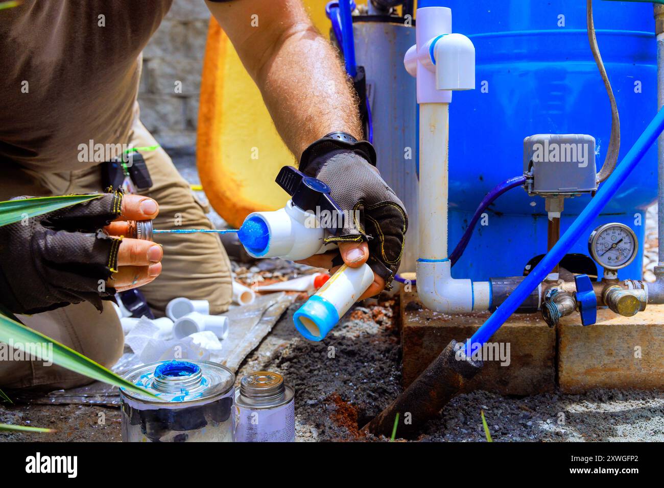 Gluing pvc pipe, plumber applies glue connected to water supply artesian well system pump house Stock Photo