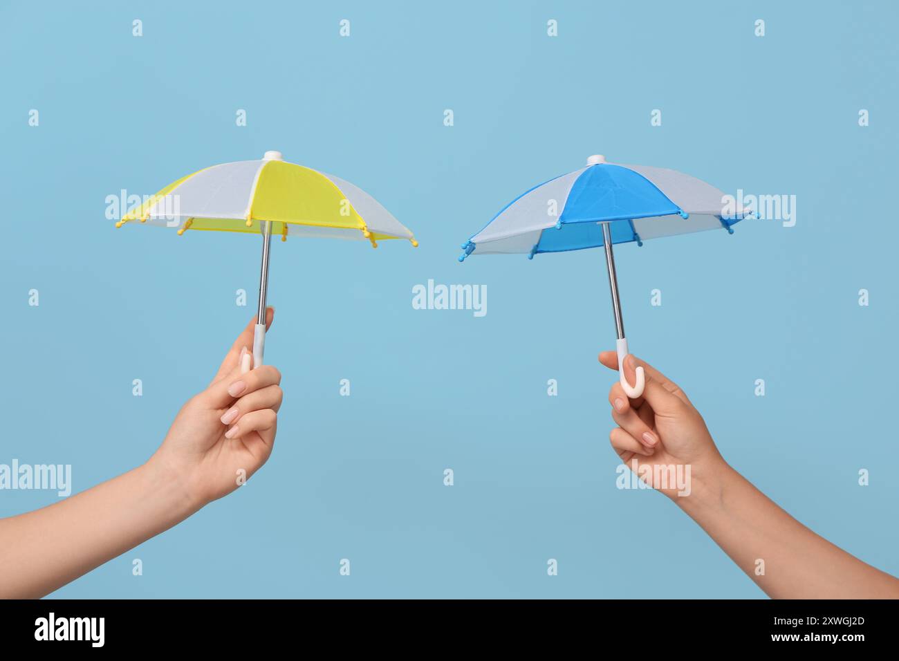 Female hands with different mini umbrellas on blue background Stock Photo