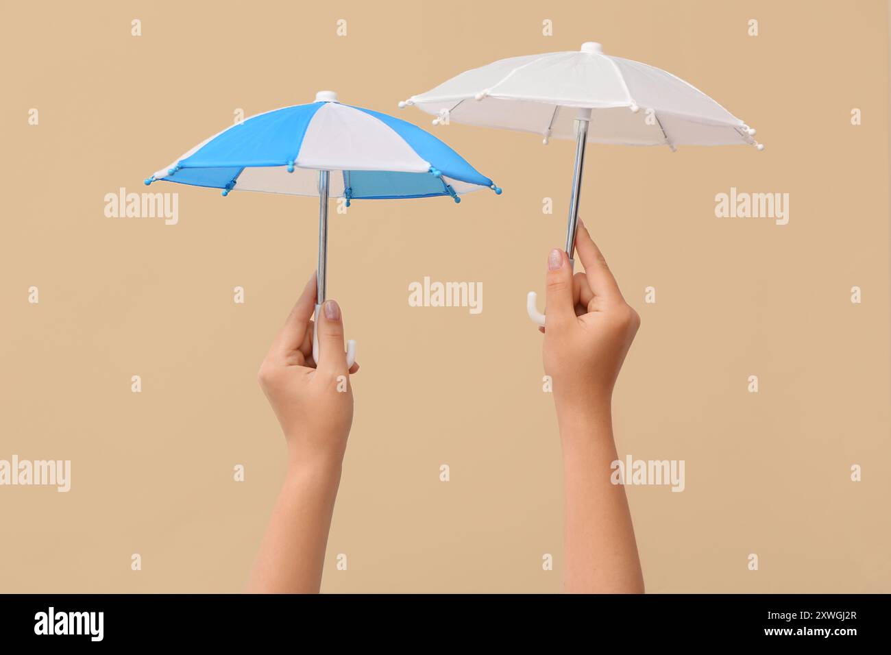 Female hands with different mini umbrellas on beige background Stock Photo