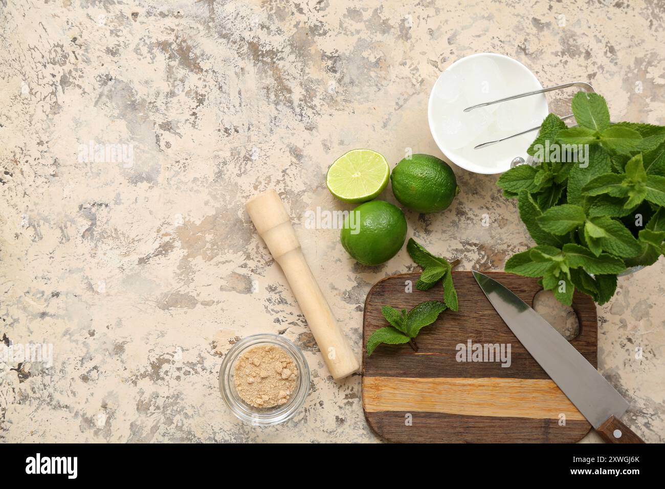 Wooden cutting board, pestle, knife and ingredients for preparing mojito on grunge background Stock Photo