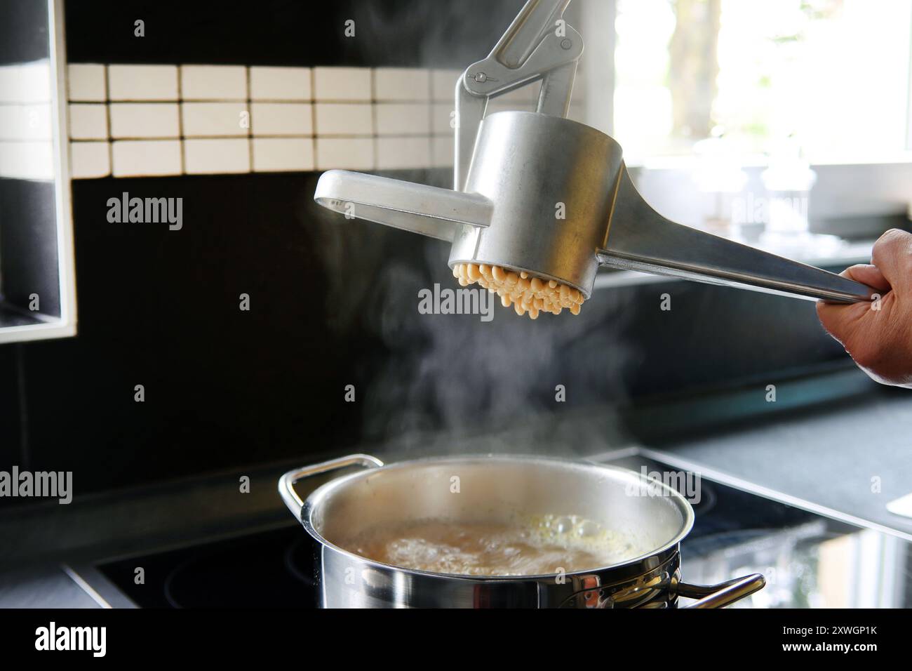 Spaetzle dough is pressed through a spaetzle press Stock Photo