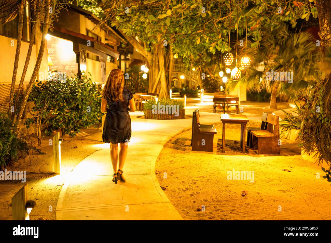 Woman Waking Along Path at Night, Almond Beach Resort, Hopkins, Belize Stock Photo