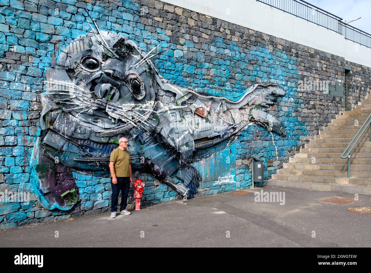 Tourist posing for photo in front of Sea Lion trash sculpture by Artur Bordalo, Bordalo II, Câmara de Lobos harbour, Madeira Island, Portugal Stock Photo