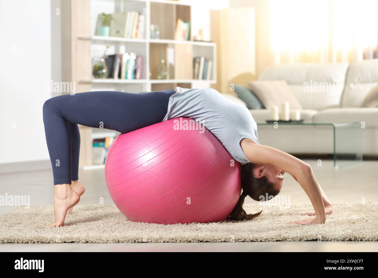 Side view portrait of a woman exercising at home with a fitness ball ...