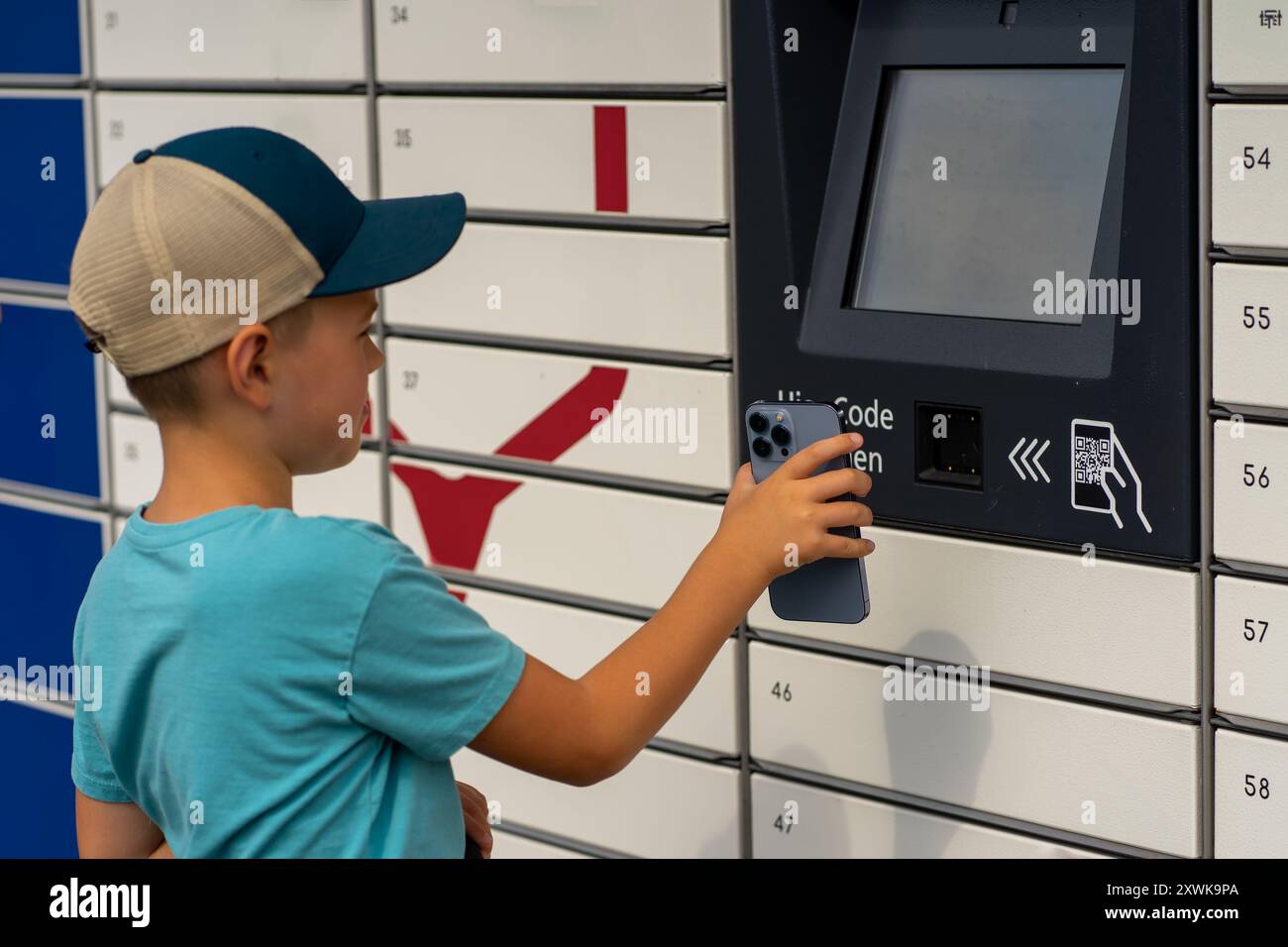 A boy receives a parcel in one of the parcel lockers Stock Photo