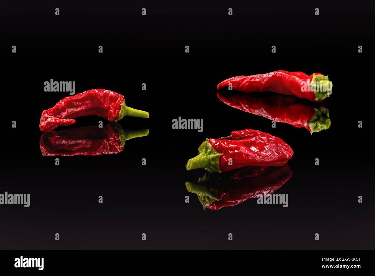 Three red chili peppers on a black background, copy space Stock Photo