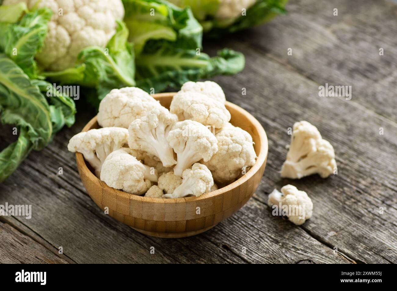 Fresh raw organic cauliflower with leaves on rustic background, uncooked vegetable Stock Photo